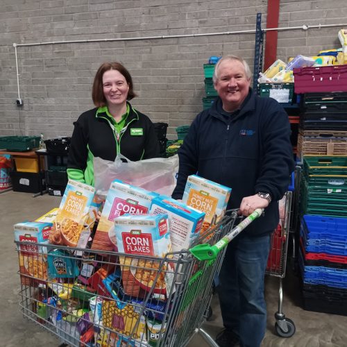 Two people with a cart of food donations