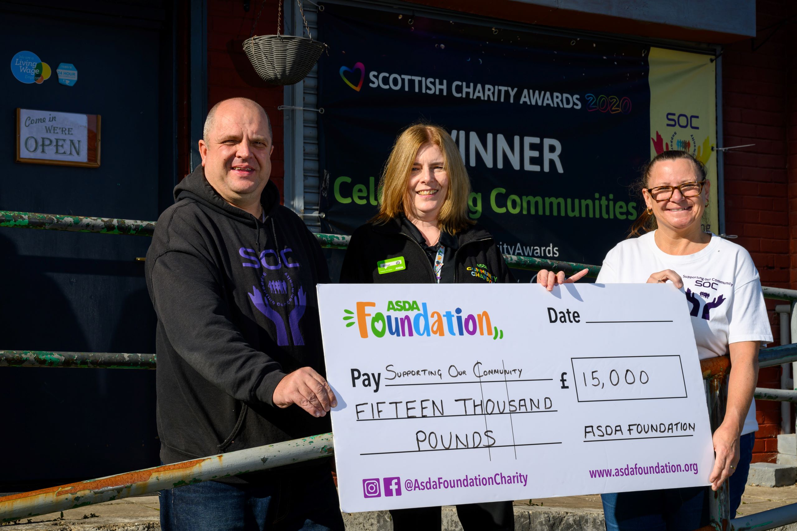 Three people holding a large Asda Foundation cheque