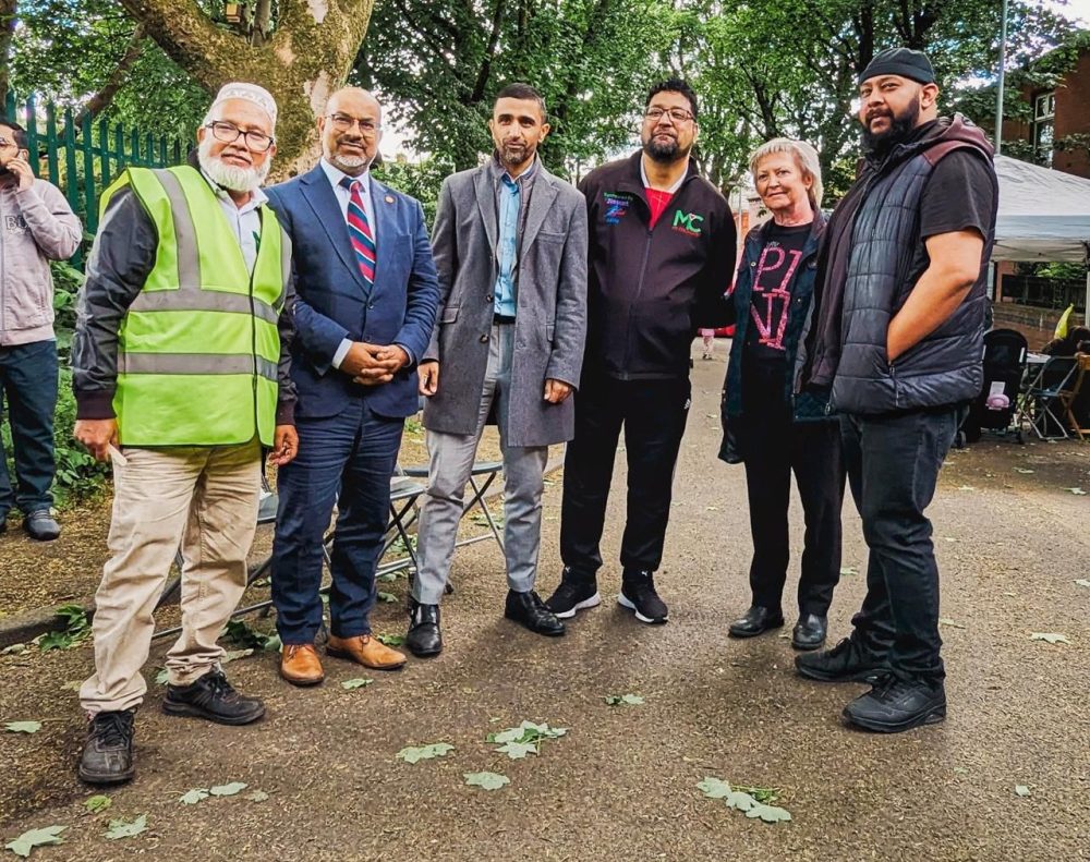 Six people stand outdoors on a path with greenery behind them, including Asda Chadderton’s Community and Customer Champion.