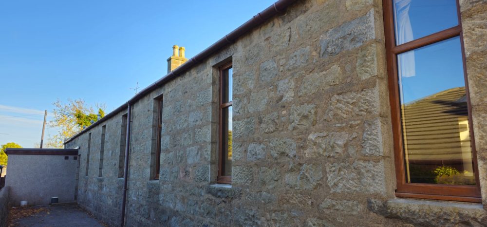 Stone building with tall windows and a clear blue sky.