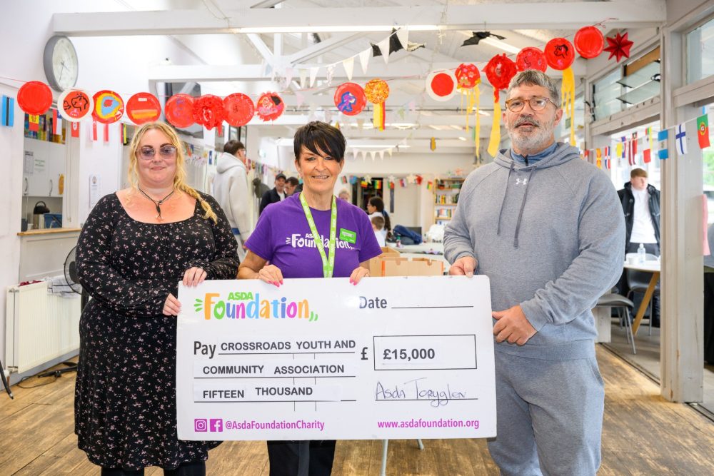 Crossroads Youth and Community Association representatives and Toryglen’s Community and Customer Champion holding a £15,000 grant cheque inside The Barn community centre.
